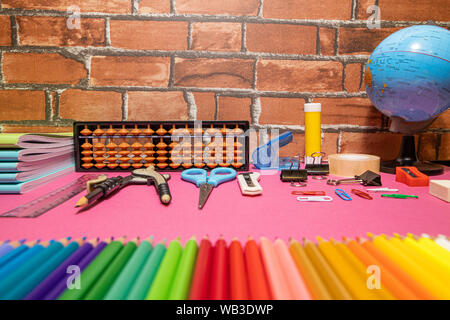 School supplies on pink board and brick background. Education, back to school concept with copy space Stock Photo