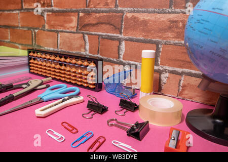 School supplies on pink board and brick background. Education, back to school concept with copy space Stock Photo