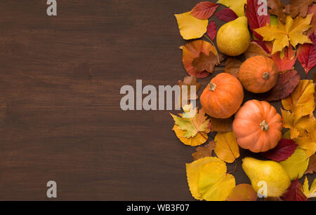 Autumn foliage with three decorative pumpkins on wood Stock Photo