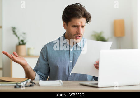Confused Guy Reading Mail Letter Or Debt Notification Indoors Stock Photo