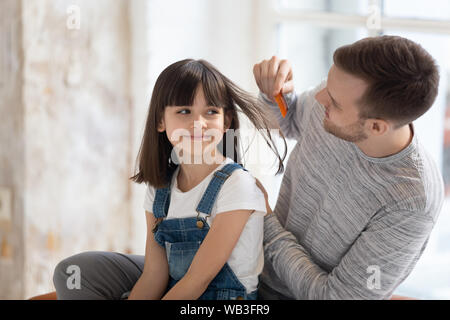 Loving young father doing brushing hair of cute kid daughter Stock Photo