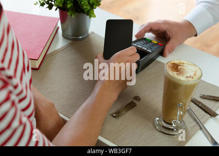 Customer making wireless or contactless payment using smartphone, nfc payment Stock Photo
