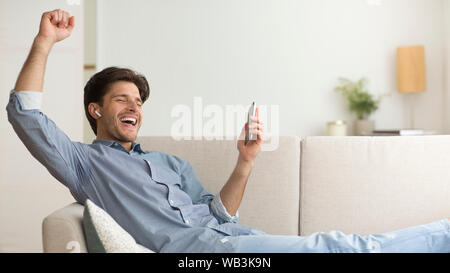 Guy Enjoying Listening To Music In Wireless Earphones At Home Stock Photo