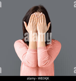 Young caucasian woman hiding her face from camera Stock Photo