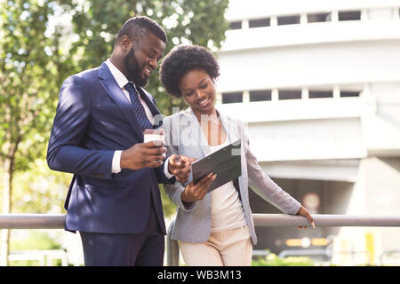 Two smiling coworkers discussing new project while standing outdoors Stock Photo