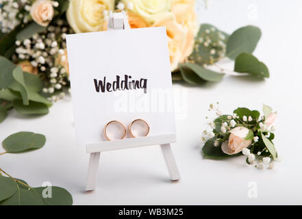 Black text and golden rings on easel, roses background Stock Photo
