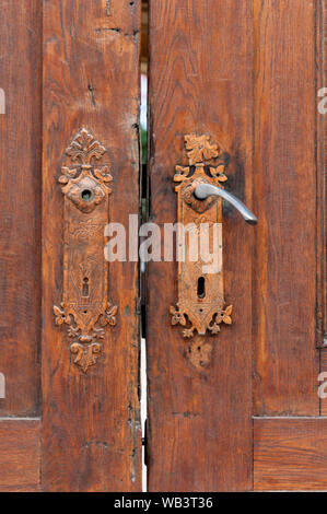 Old door knob on a wooden door. Weathered, broken and repainted. Stock Photo