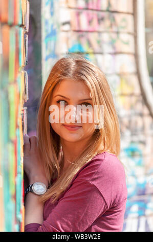 Outdoors portrait of a woman, near a colored wall Stock Photo