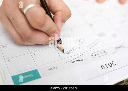 Picture of Man holding Calendar and marking on date. Isolated on white background. Stock Photo