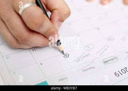 Picture of Man holding Calendar and marking on date. Isolated on white background. Stock Photo