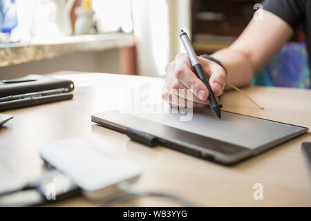 Professional photo editor or graphic designer retouching images with stylus pen in hand.Retoucher working on photos with tablet device.Freelance photo Stock Photo