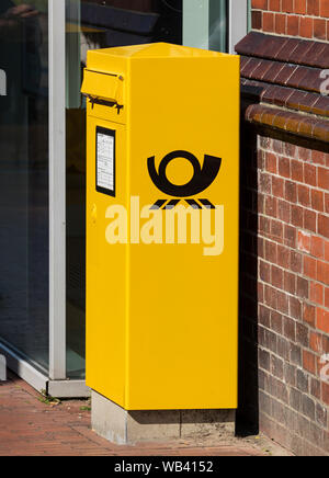 Stade, Germany - August 22, 2019: Yellow letterbox with logo of Deutsche Post Stock Photo