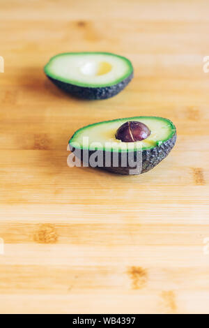 An avocado cut in half, on a table in the kitchen with the seed Stock Photo