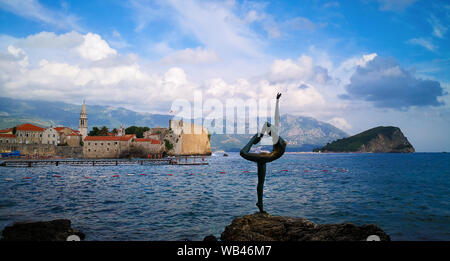 never forget: Statue of a ballerina Dancer of Budva against the Old Town of Budva near Mogren beach fortress, Budva, Montenegro. Stock Photo