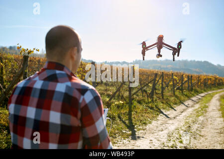 Young man filming vineyard with modern drone Stock Photo