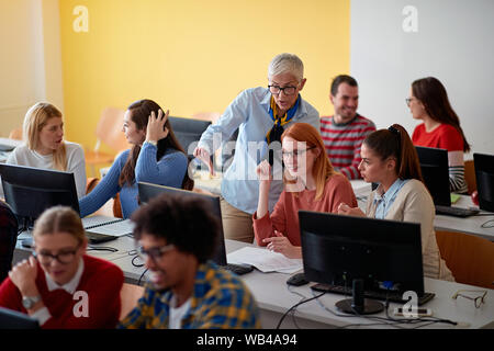 lecturer helping smiling students on project on university Stock Photo