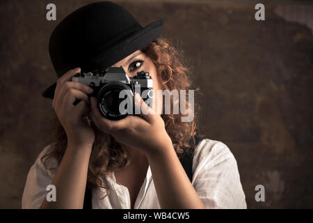 Woman Photographer with Bowler and Suspenders Holding a Camera Stock Photo