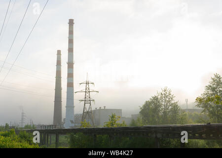 industrial landscape - pipelines and chimneys in the morning mist Stock Photo