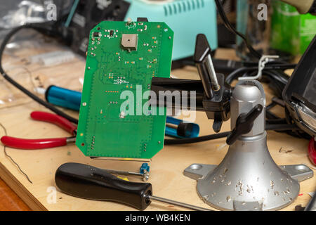 Printed circuit board in vice on workbench for repair Stock Photo