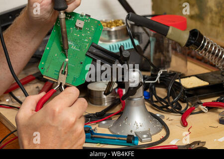 Hand soldering on printed circuit board on workbench Stock Photo