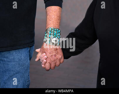 A senior couple wearing Native American jewelry hold hands while visiting the annual Santa Fe Indian Market in New Mexico, USA Stock Photo