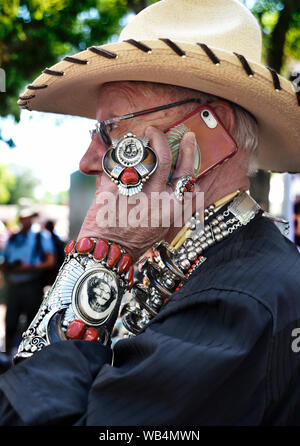 A tourist wearing Native American jewelry uses his smart phone at the annual Santa Fe Indian Market in New Mexico, USA Stock Photo