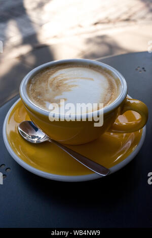 Yellow cup of coffee on the table. A fresh morning in a street cafe. Stock Photo