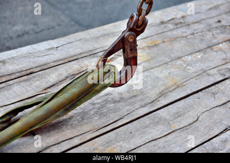 Heavy lifting crane hook with closed safety catch hooked onto lifting straps on wooden planks Stock Photo