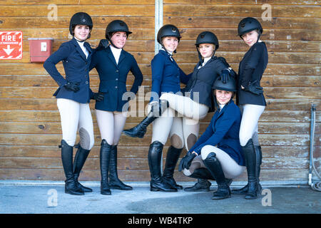 A group of equestrian high school girls dressed in show clothes are posing for the camera Stock Photo