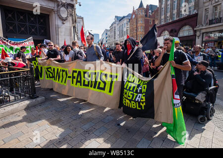 London, UK. 24th August 2019. Anti-fascists march to oppose a protest at the BBC by Tommy Robinson supporters who claim he is in jail for journalism. He was sentenced to 9 months for 3 offences outside Leeds Crown Court which could have led to the collapse of a grooming gang trial, and has previous convictions for violence, financial and immigration frauds, drug possession and public order offences. Police kept the two groups apart. Robinson supporters were later joined by marchers from Trafalgar Square, and a larger group from Stand Up to Racism came to join Antifa. Peter Marshall/Alamy Live Stock Photo