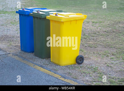 three lockable  recycle trash bins (blue, green, yellow) used for different materials Stock Photo