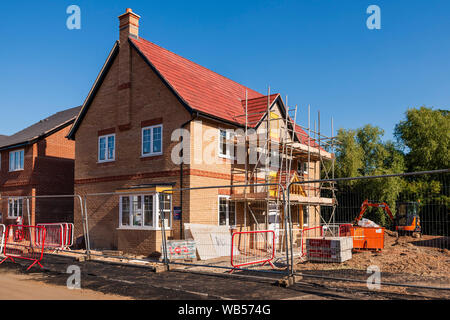 New build homes, England, UK. New house building site with scaffolding in summer. New housing estate being built. Stock Photo