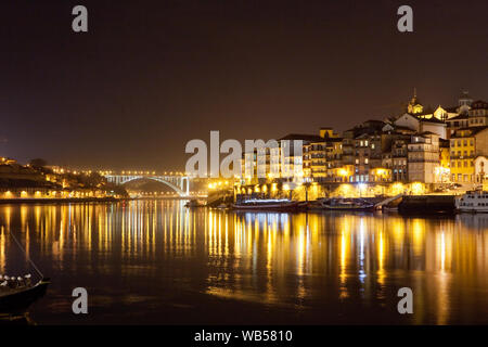 The river Douro (Rio Douro) and the picturesque city of Porto with the Ponte da Arrábida,in the background seen at night, Portugal. Stock Photo
