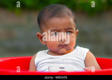 A baby boy sitting on a Red Bowl Stock Photo
