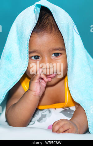 A six months age asian baby boy is laughing and joking under the towel. Stock Photo