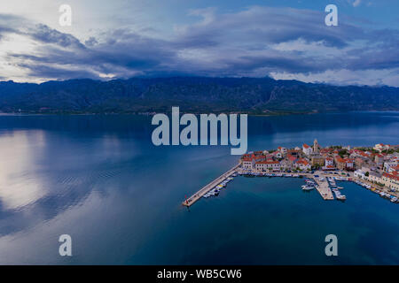 An aerial shot of a calm sea with mountains in the background under the ...