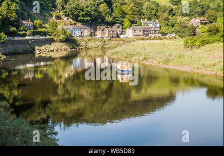 The village of Tintern alongside the River Wye, Afon Gwy in welsh, in the Wye Valley, Monmouthshire, an AONB with the added bonus of a moored boat. Stock Photo