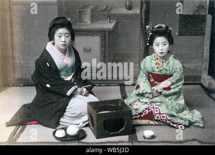 [ 1890s Japan - Japanese Women in Kimono ] —   Two women in kimono are seated on tatami (rice mats). A hibachi, a tea pot and two cups are in front of them.  Original text: 'An Informal Afternoon Tea.'  Albumen photograph sourced by Kozaburo Tamamura (1856-1923?), 1890s, for 'Japan, Described and Illustrated by the Japanese', Shogun Edition edited by Captain F Brinkley. Published in 1897 by J B Millet Company, Boston Massachusetts, USA.  19th century vintage albumen photograph. Stock Photo