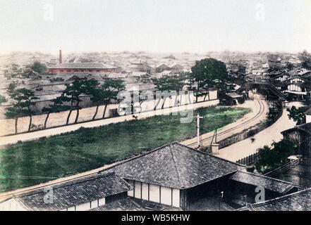 [ 1880s Japan - Railway Line in Osaka ] —   Railway tracks of Hankai Tetsudo winding through southern Osaka. Started in 1885 (Meiji 18), the railroad connected Osaka with Sakai.   In 1898 the company merged with Nankai Railway; it is now known as Nankai Electric Railway.   Below the overpass, the railroad crossing can be seen. At this time, trains still stopped at crossings. Somewhere behind the large tree is Nanba Railway Station. Shot between 1886 and 1890.   19th century vintage albumen photograph. Stock Photo