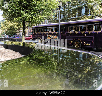ASHEVILLE, NC, USA-21 AUGUST 2019: A LaZoom tourist bus passes a reflective water display in Pack Square park. Stock Photo