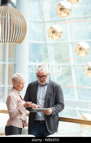 Portrait of two senior business partners discussing work and using digital tablet, copy space Stock Photo