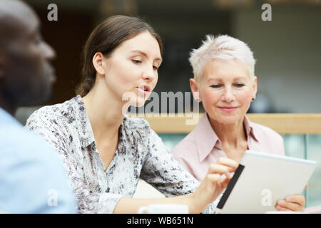 Portrait of young businesswoman using digital tablet during meeting with colleagues, copy space Stock Photo