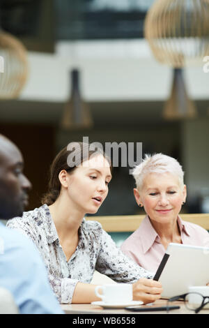 Portrait of young businesswoman using digital tablet during meeting with group of colleagues, copy space Stock Photo