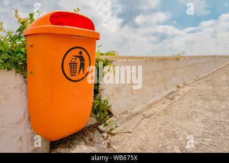 Plastic trash can with recycle sign on it in the park. Container for garbage disposal in the city. Small bin for collecting waste and protect the envi Stock Photo