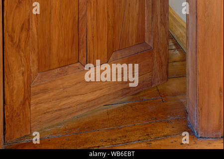 A wooden door is open just a crack, making you wonder what is behind it Stock Photo