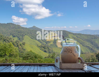 Isolated Iced coffee in a glass jar on Bamboo flooring Background mountains with clipping path. Stock Photo