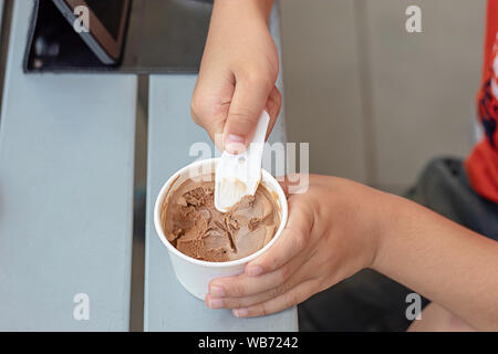 Hand boy holding the spoon Ice cream scoop in a cup. Stock Photo