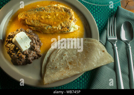 A stuffed Mexican chile with Mexican rice and beans on a plate. Stock Photo