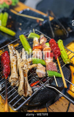 Vertical photo of skewers and chicken legs on charcoal stove Stock Photo