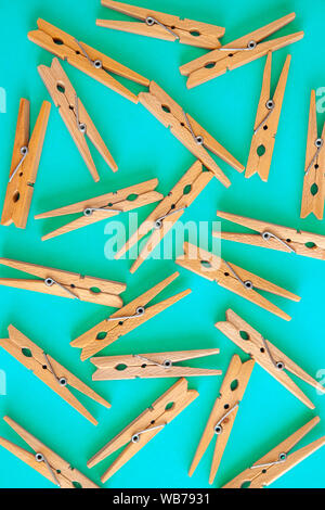 Wooden yellow clothespins are scattered on a cyan-blue background. Frame of clothespins. View from above. Copy space. Flat lay. The concept is natural Stock Photo